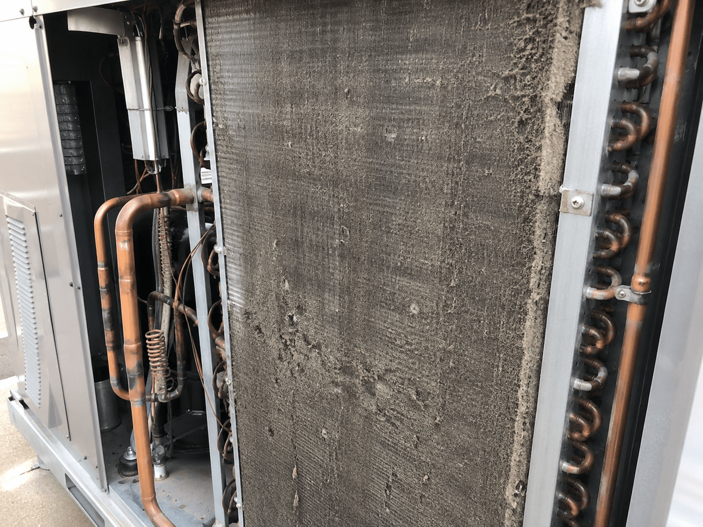 Dirty AC coil with heavy dust and debris buildup before professional cleaning