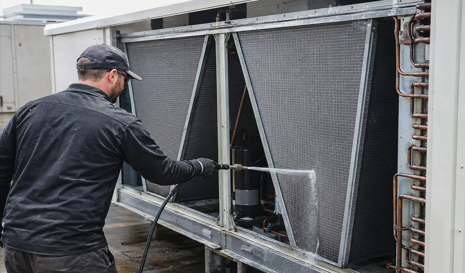 Technician cleaning the coils of a large commercial central air conditioning system