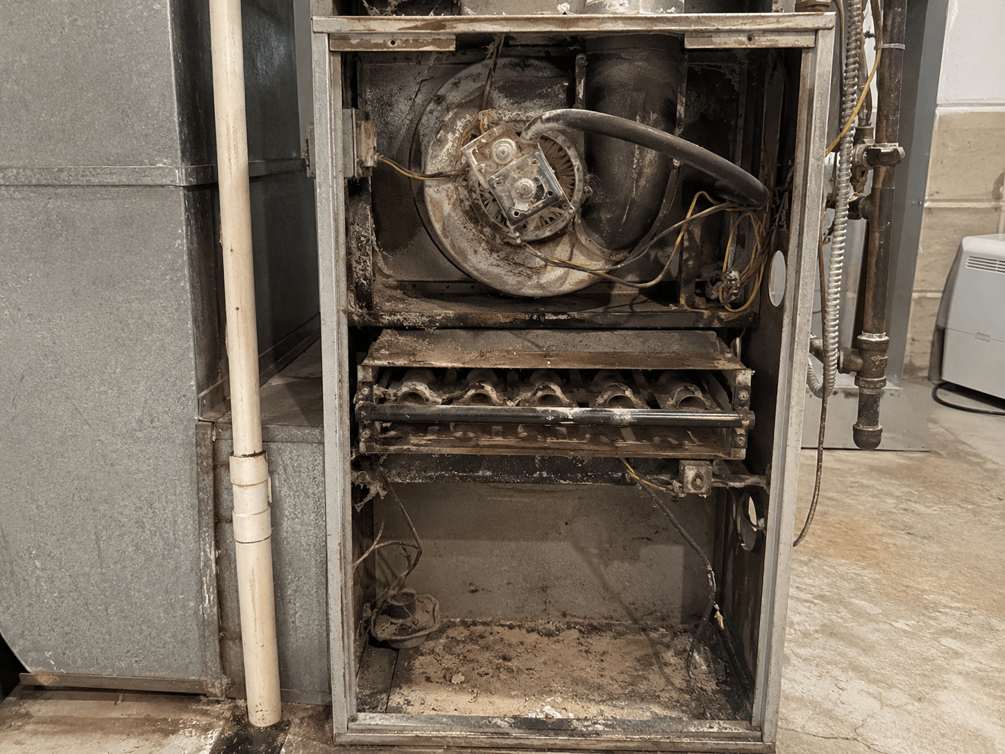 Dirty furnace interior with heavy dust and debris buildup before professional cleaning