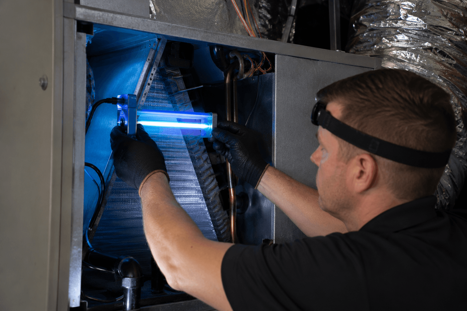 Kemah Air Duct Cleaning Texas technician installing a UV light inside a central air conditioning system